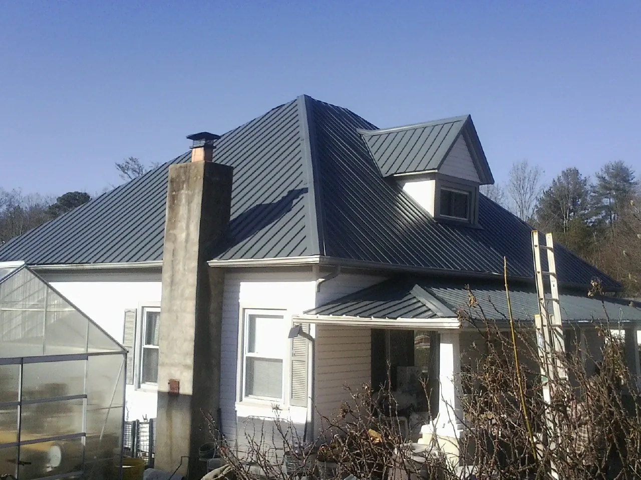 Dark blue standing seam metal roof on a white farmhouse with dormer — Slate & Tile Roof Repair by Roofing Brothers in Findlay