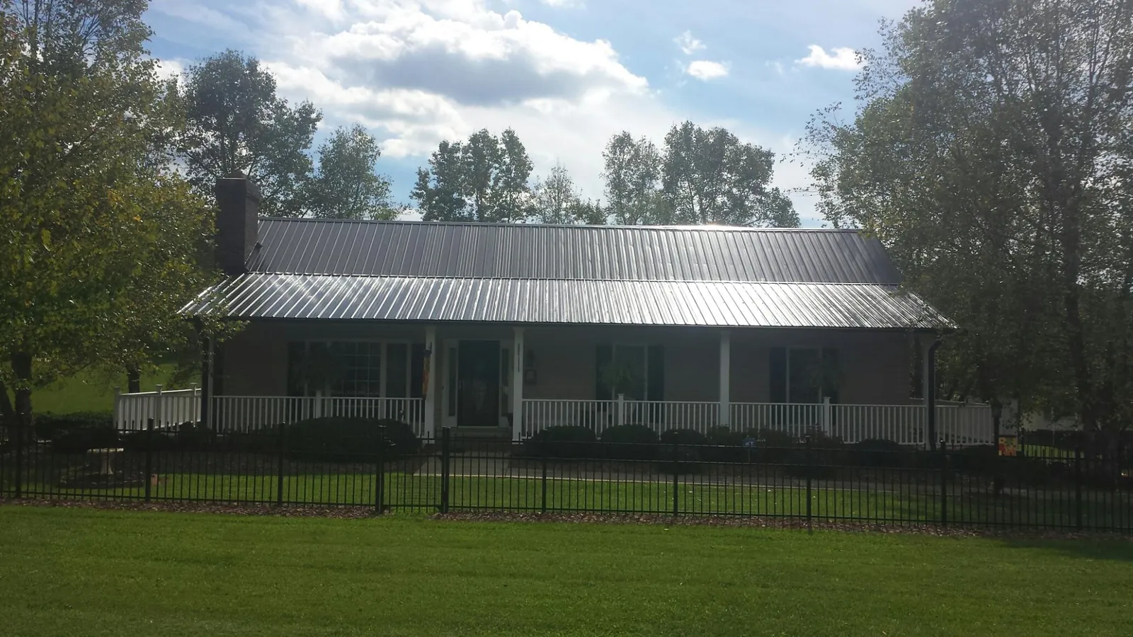Gray metal roof on a brick ranch with a full width front porch — Gutter Guard Installation work by our crew in Findlay