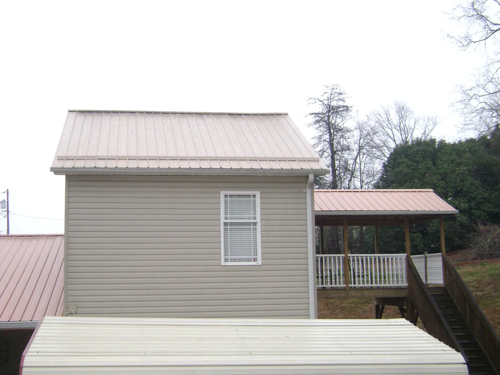Tan metal roofs on a two story addition and attached porch, from a Roof Replacement job in Findlay