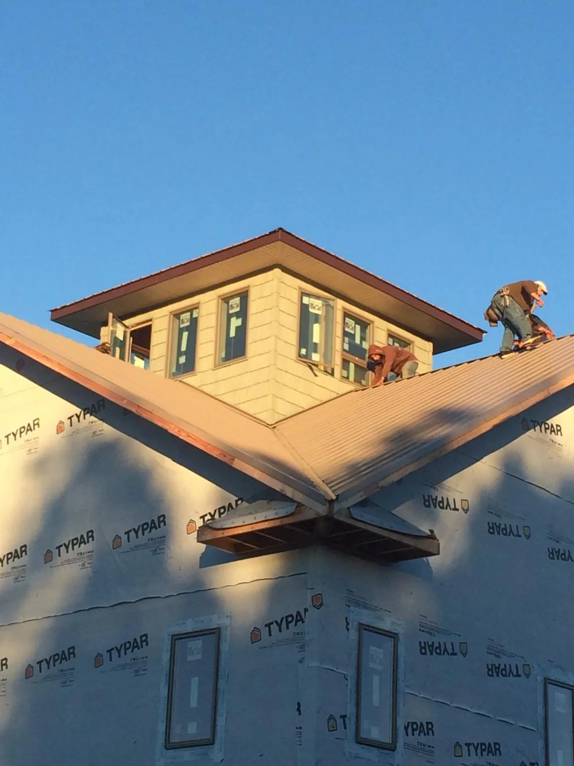 Roofers working around a rooftop cupola on a new metal roof at sunset — Roof Waterproofing in Findlay by Roofing Brothers
